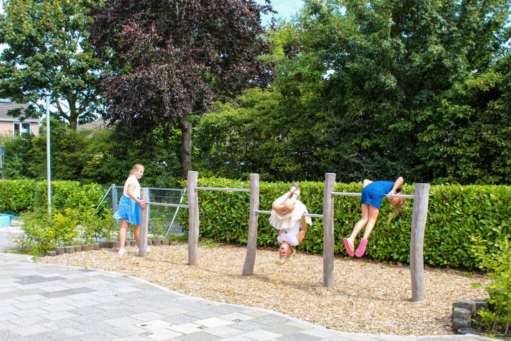 Kinderen bij duikelrekken op kleuterplein
